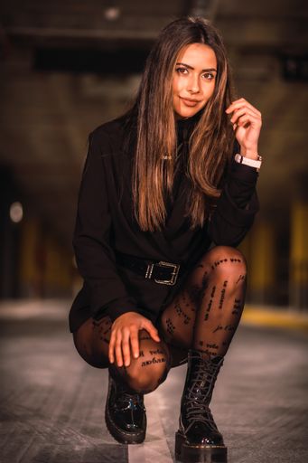 A shallow focus of a brunette female wearing shorts with boots and posing in an underground car park