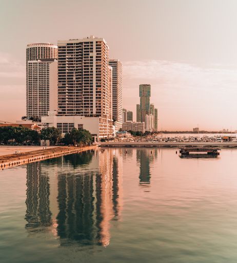 A vertical shot of a lake reflecting the bridge and city buildings on a cloudy day