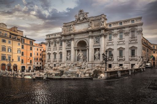 A Dramatic evening shot of the Trevi Fountain in Rome, Italy with a cloudy sky in the background