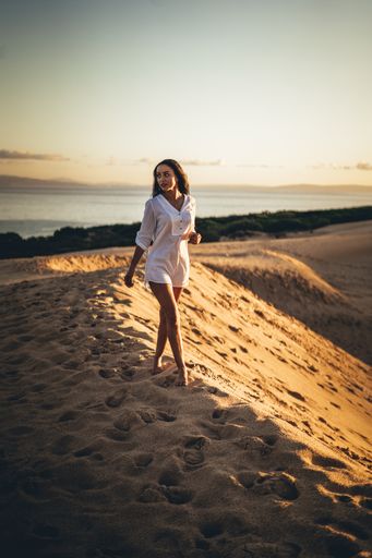 A vertical shot of a young Caucasian woman walking in the desert