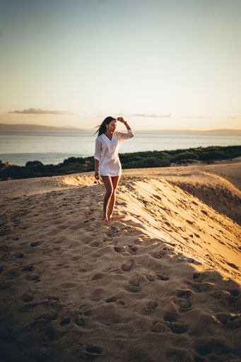 A vertical shot of a young Caucasian woman walking in the desert