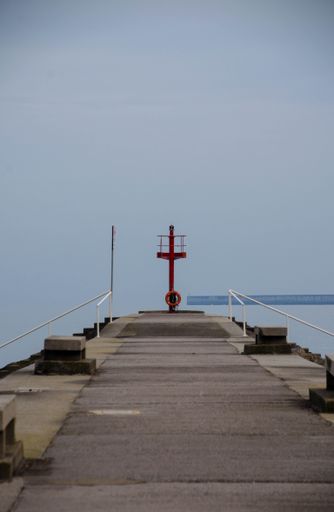 A vertical shot of a pier leading to the ocean under the clear sky
