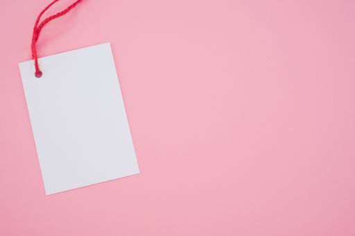 A blank tag with a red string on a pink background