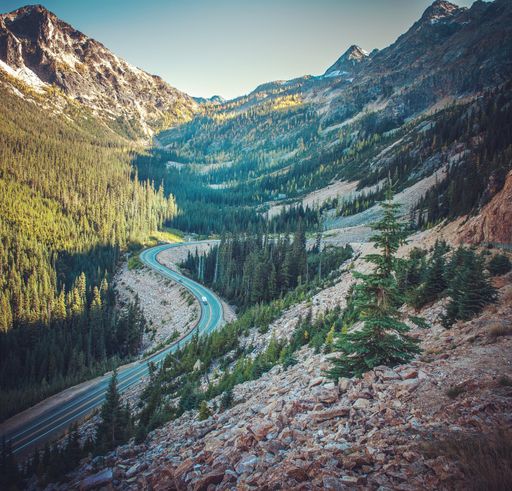 A beautiful high angle shot of a curvy narrow road in the countryside with breathtaking high and steep rocky mountains on both sides