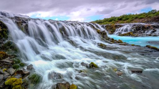 A beautiful view of a waterfall surrounded by rocky cliffs in Iceland