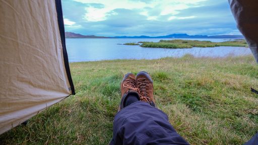 The feet of a person lying in a tent and enjoying the beautiful view of the sea in Iceland