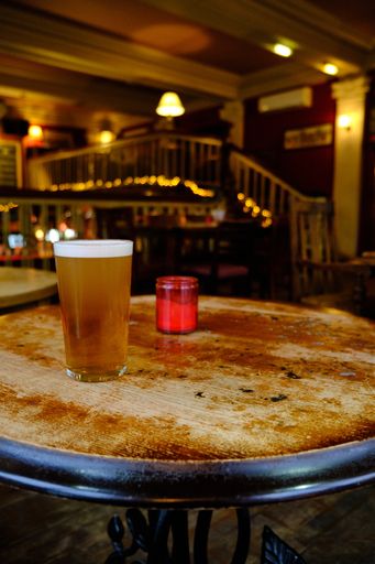 A closeup of a glass of beer on the table under the lights in the bar with a blurred background