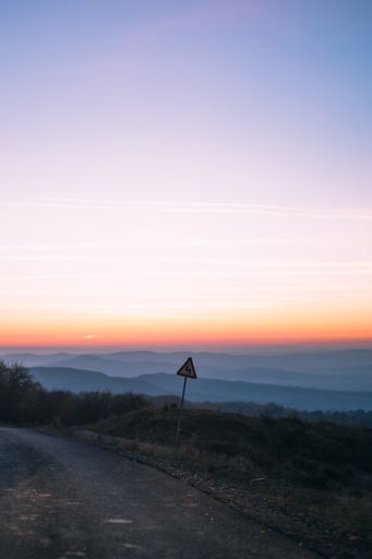 A vertical shot of a road with mountains in the background at scenic sunset