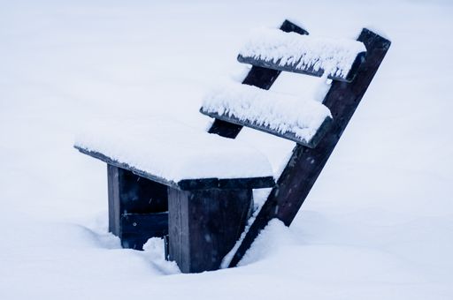 A closeup shot of a wooden bench in the snow standing in the street