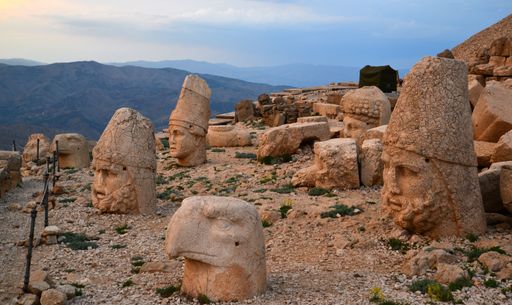 The ancient sculptures on Mount Nemrut at sunset with a cloudy sky in the background in Turkey