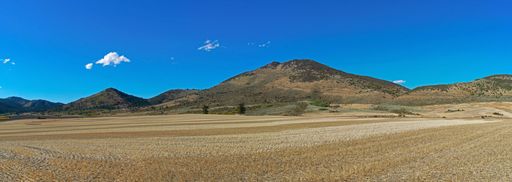 A panoramic shot of a mountainous area and an agricultural fieunder the blue sky