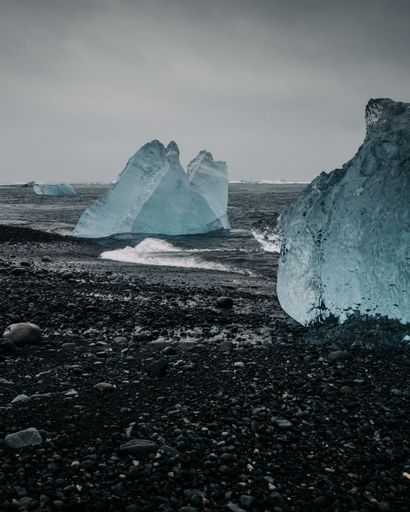 A vertical shot of the Diamond Beach, with large chunks of chiseled ice sit on black sand in Jokulsarlon glacier lagoon, Iceland