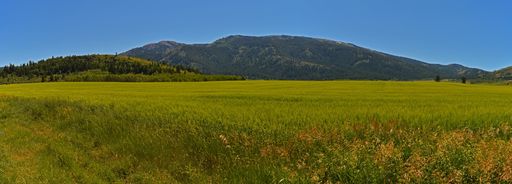 A panoramic shot of a mountainous area and an agricultural field under the blue sky
