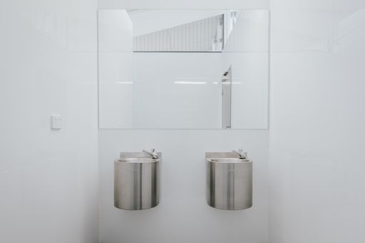 A stainless lavatory with a mirror inside a restroom
