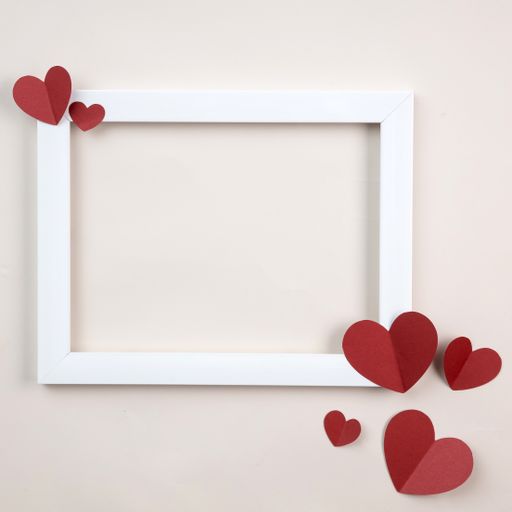 A closeup shot of frame and paper hearts against a white background with copy space