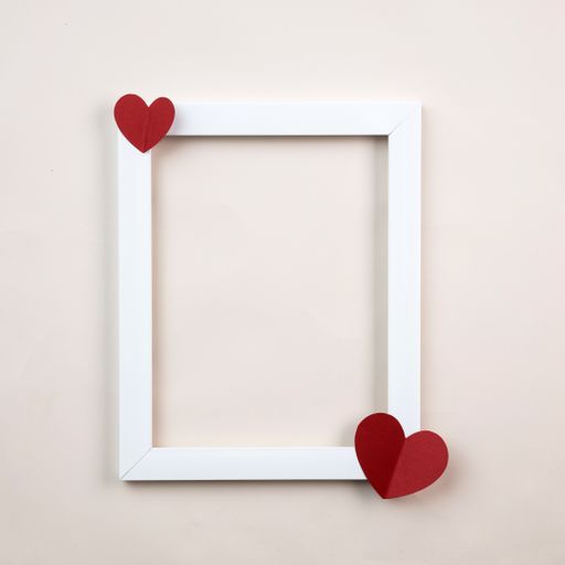 A closeup shot of frame and paper hearts against a white background with copy space