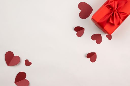 A top view of red gift box with paper hearts against white background with copy space