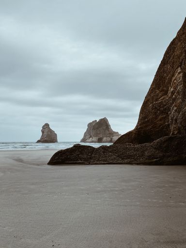 A vertical shot of big rock on the sandy seashore