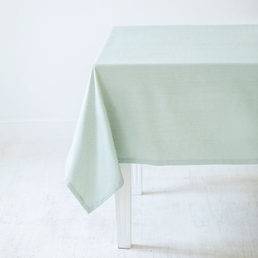 A light green decorative tablecloth on a table on a white background
