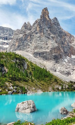 A vertical shot of a crystal clear lake surrounded by rocky hills under the sunlight