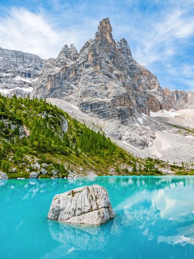 A vertical shot of a crystal clear lake surrounded by rocky hills under the sunlight