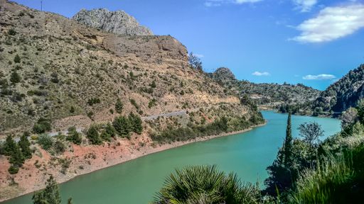 A wide angle shot of a river flowing next to the mountains during daytime