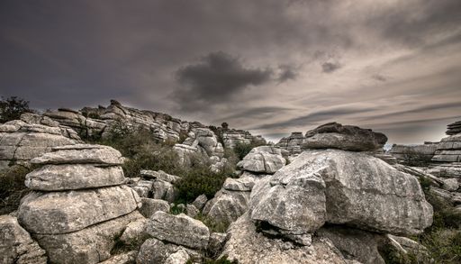 A closeup shot of several grey rocks on top of each other under a cloudy sky