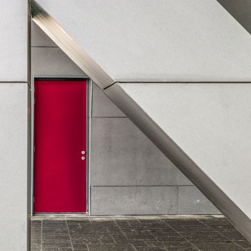 A closeup shot of the red door of a white building