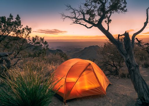 Orange tent on top of a hill at sunset