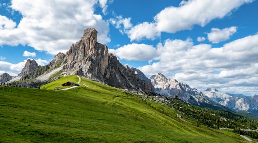 A landscape of a field surrounded by rocky hills under a blue cloudy sky in the countryside