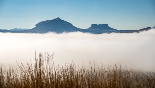 A wide angle shot of grass growing in front of the mountains covered in mist