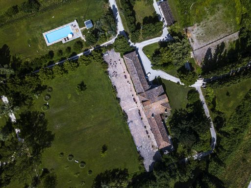 An aerial view of a residential building with a swimming pool and green trees
