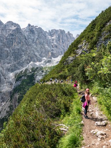 A vertical shot of a female hiker with a backpack standing on a pathway on rocky hills