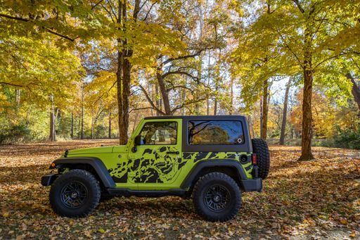A car parked among autumn leaves and trees on a fall day