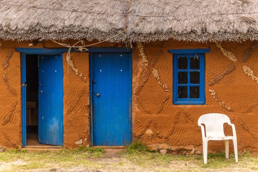 A closeup shot of the two blue doors and a window of a brown house