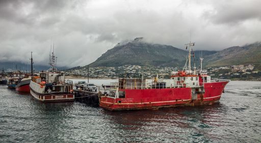 A wide angle shot of several ships on the water behind the mountain under a cloudy sky