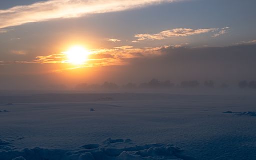 A breathtaking view of a field completely covered with snow captured at sunset