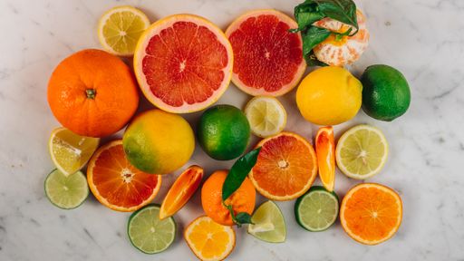 A top view of the whole and sliced citrus fruits mix on a white table