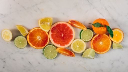 A top view of the whole and sliced citrus fruits mix on a white table