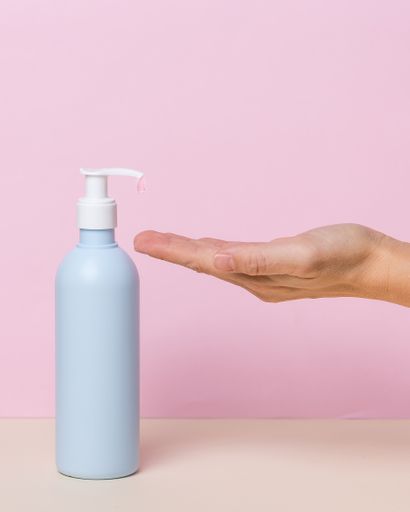 Female hand using alcohol gel sanitizer dispenser, against coronavirus . Antiseptic, Hygiene and Health concept. Minimalist style on pink background