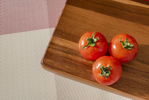A top view of delicious wet tomatoes on a red board