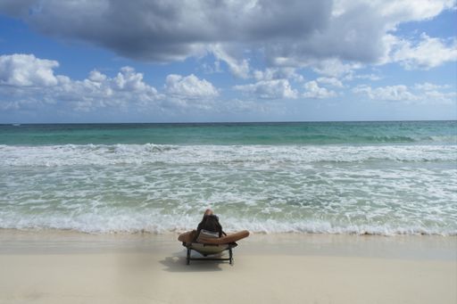 A back view of a young female on a beach chair near the sea