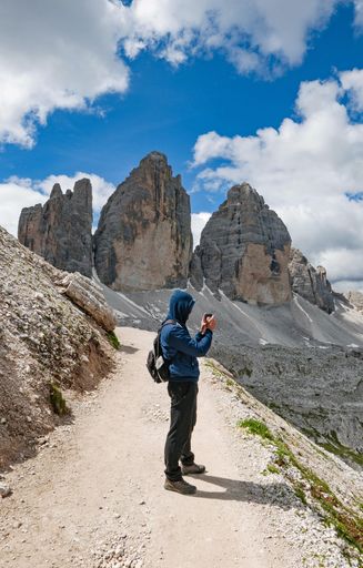 A vertical shot of a photographer taking photos from the top of a mountain peak