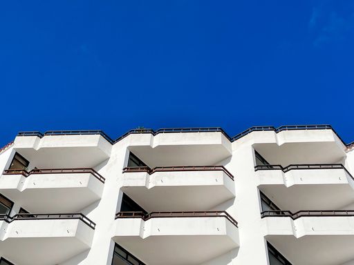 A low angle shot of a facade with yellow balconies under blue sky