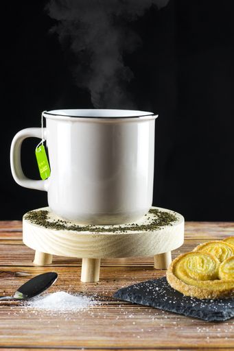 A vertical shot of a cup of hot tea accompanied by delicious puff pastry cookies