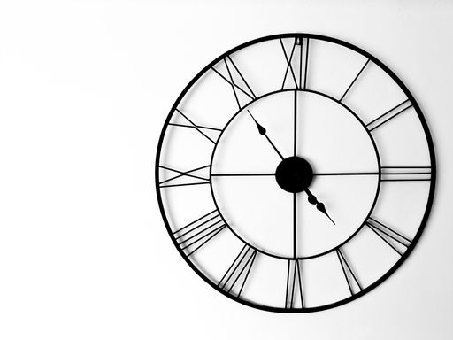 A closeup shot of a black vintage clock hanging on a white wa