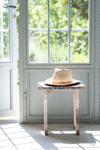 A vertical shot of a hat on an old chair in front of a door indoors
