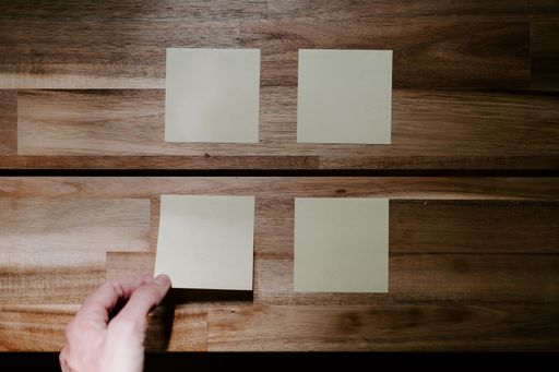 A top view closeup of a person attacking sticky note papers on a wooden table