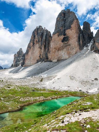 A vertical shot of a lake by the beautiful mountain peaks captured on a sunny day