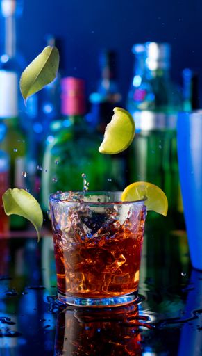 A vertical shot of a cocktail with splashes and lemons flying